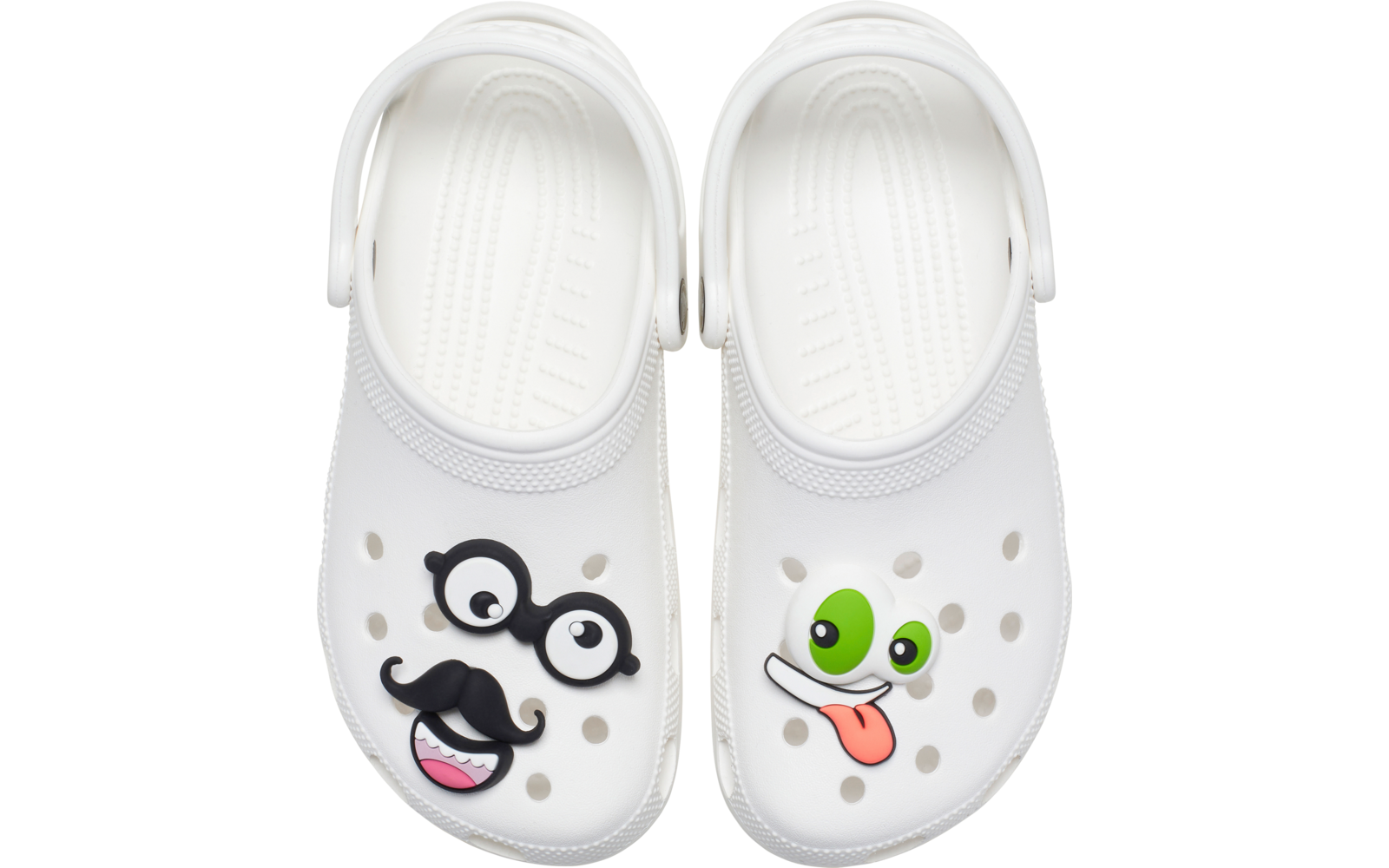Paire de sabots blancs vue de dessus. Sabot gauche avec décorations clipsées : lunettes noires et moustache, et décoration de bouche rose. Sabot droit avec décoration d'œil vert et décoration de langue tirée