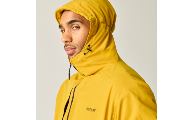 Person in gelber Kapuzenjacke, Seitenansicht, Blick zur Kamera, heller Hintergrund