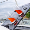 Zwei Gläser mit rotem Getränk auf einem schrägen, schwarzen Deck auf einem Boot am Wasser