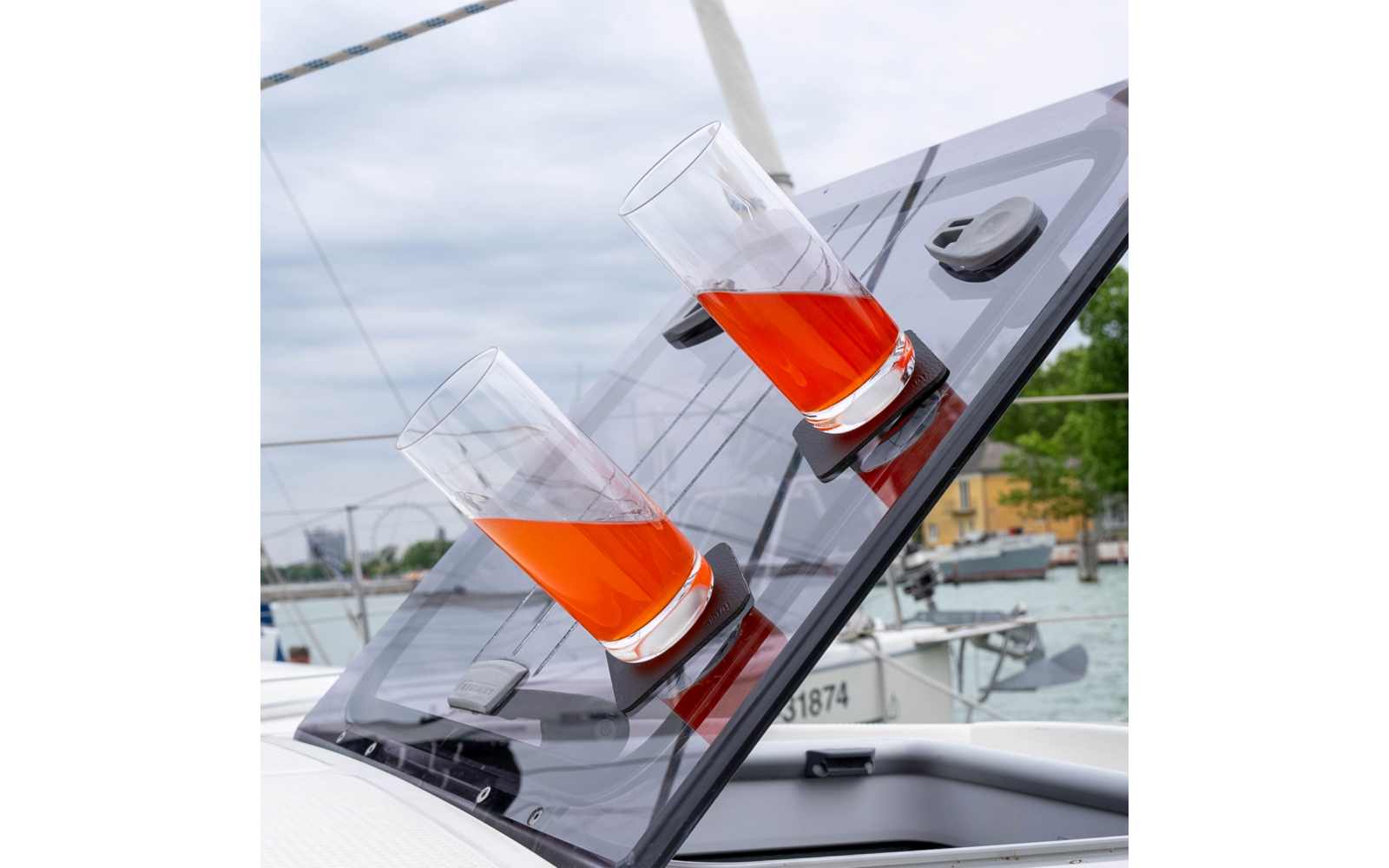 Zwei Gläser mit rotem Getränk auf einem schrägen, schwarzen Deck auf einem Boot am Wasser