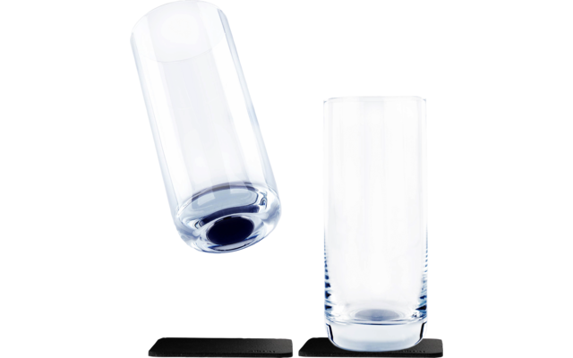 Ein umgekippter leerer Glasbehälter neben einem aufrecht stehenden leeren Glas auf schwarzen Unterlagen