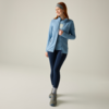Mujer con chaqueta azul claro, camiseta azul, mallas oscuras, cinta en la cabeza, calcetines grises y botas de senderismo grises sobre fondo claro
