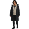 Frau mit dunklem langen Mantel, beiger Kapuzenpullover und schwarzer Hose