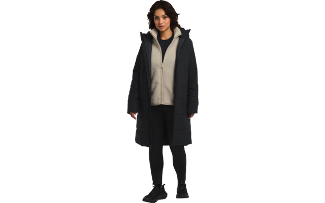 Frau trägt langen schwarzen Mantel, grauen Pullover, schwarze Hose und schwarze Schuhe