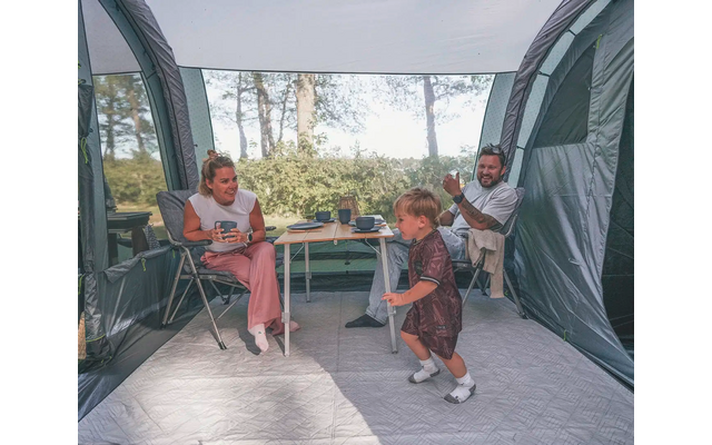 Drei Personen sitzen vor einem Zelt, zwei sitzen auf Stühlen und eine Person kniet auf dem Boden