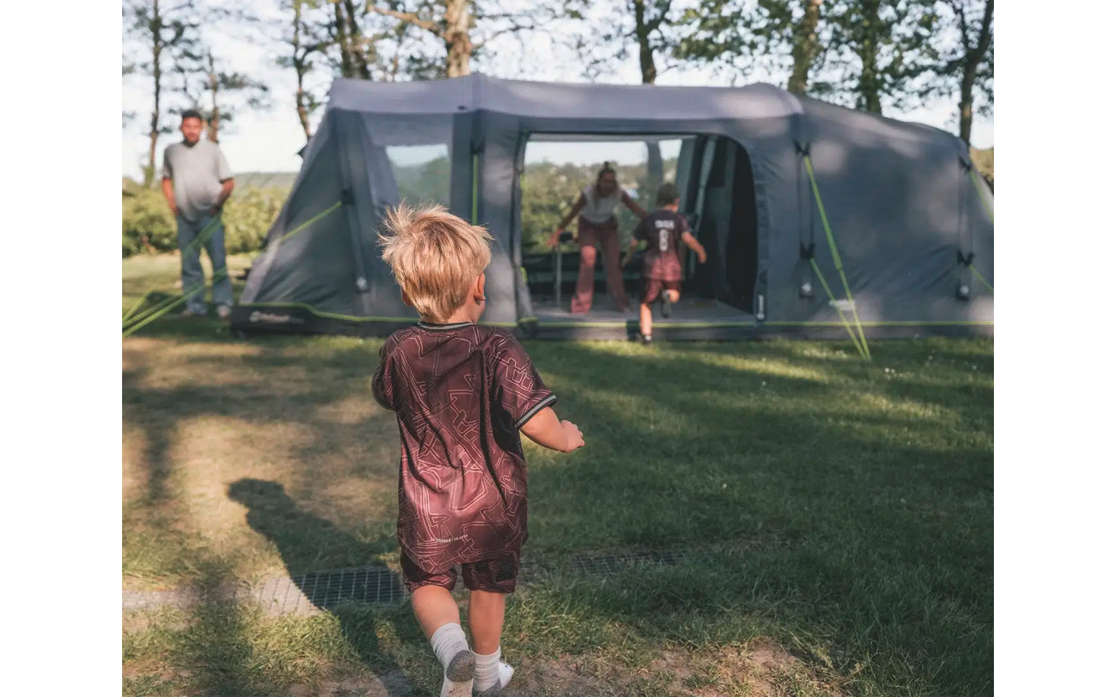 Kinder spielen vor einem großen grauen Zelt im Wald