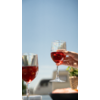 Twee glazen met rode drank tegen heldere lucht, hand die een glas vasthoudt