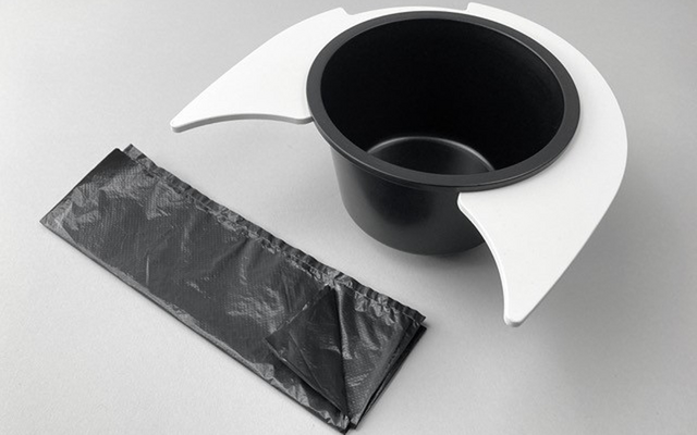 Gobelet noir avec supports blancs et un sac plastique noir emballé sur une surface grise