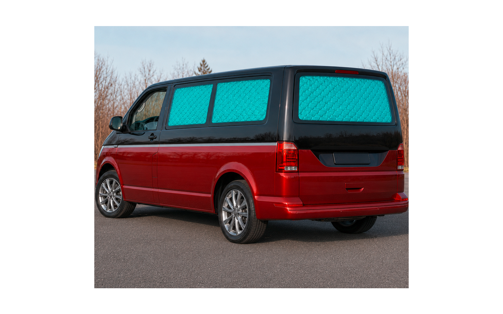 Red van, blue quilted window covers, parked on a road; leafless trees and sky in the background
