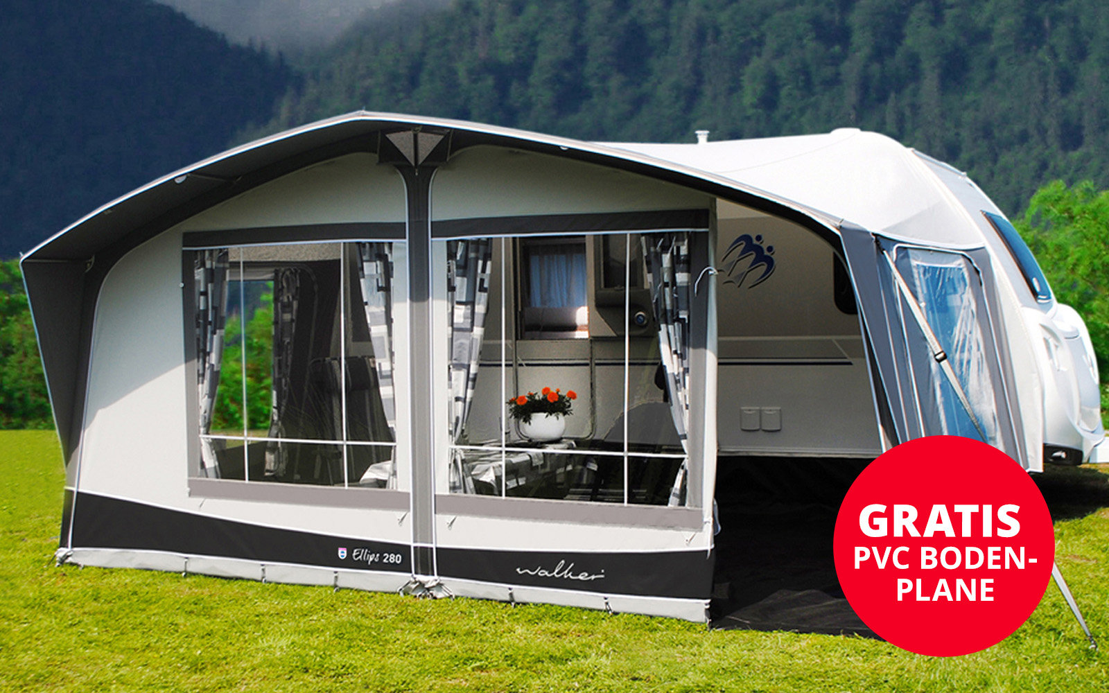 Grande tente blanche avec rideau ouvert sur de l'herbe verte, montagnes et forêt en arrière-plan