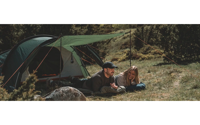 Zwei Personen sitzen auf einer Decke neben einem aufgestellten Zelt im Wald
