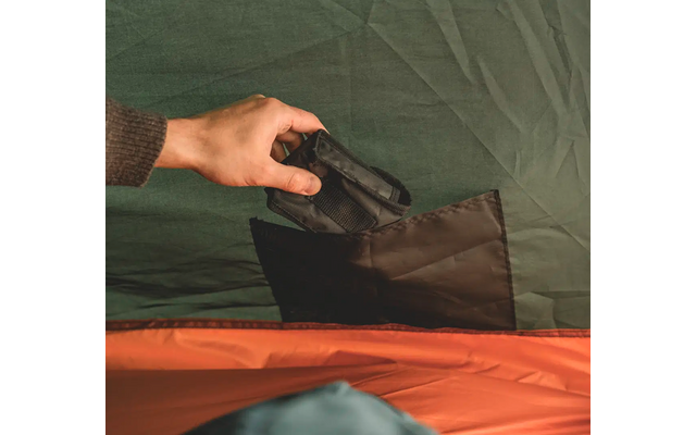 Hand legt eine schwarze Tasche in ein Zelt