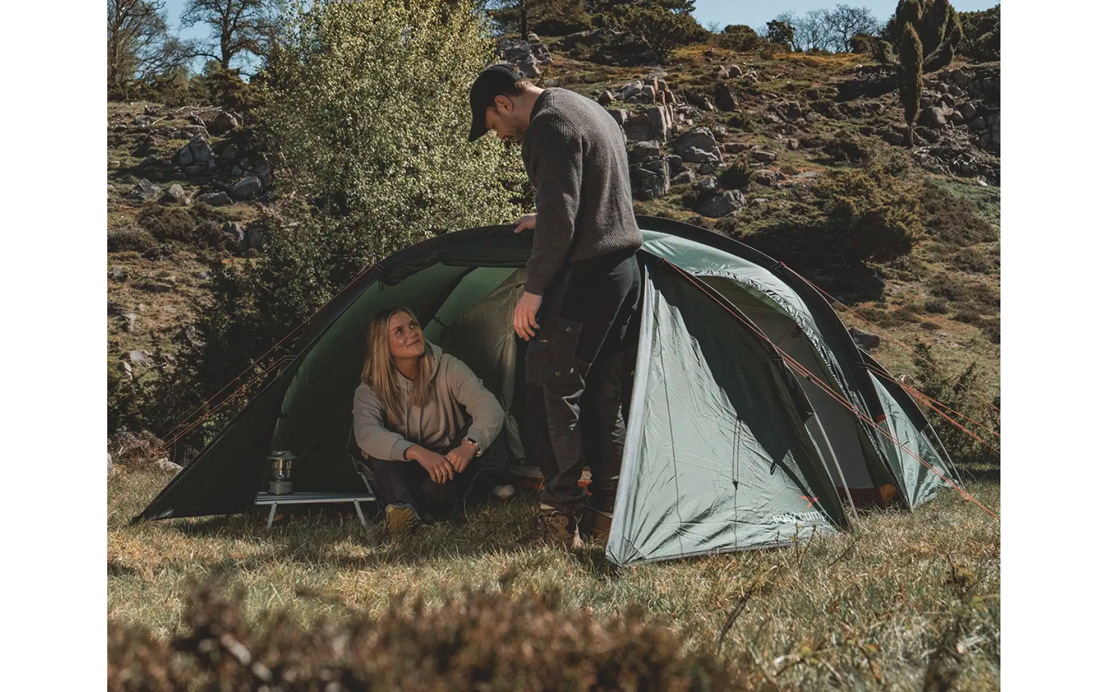 Zwei Personen beim Aufbauen eines Zeltes in einer felsigen Landschaft