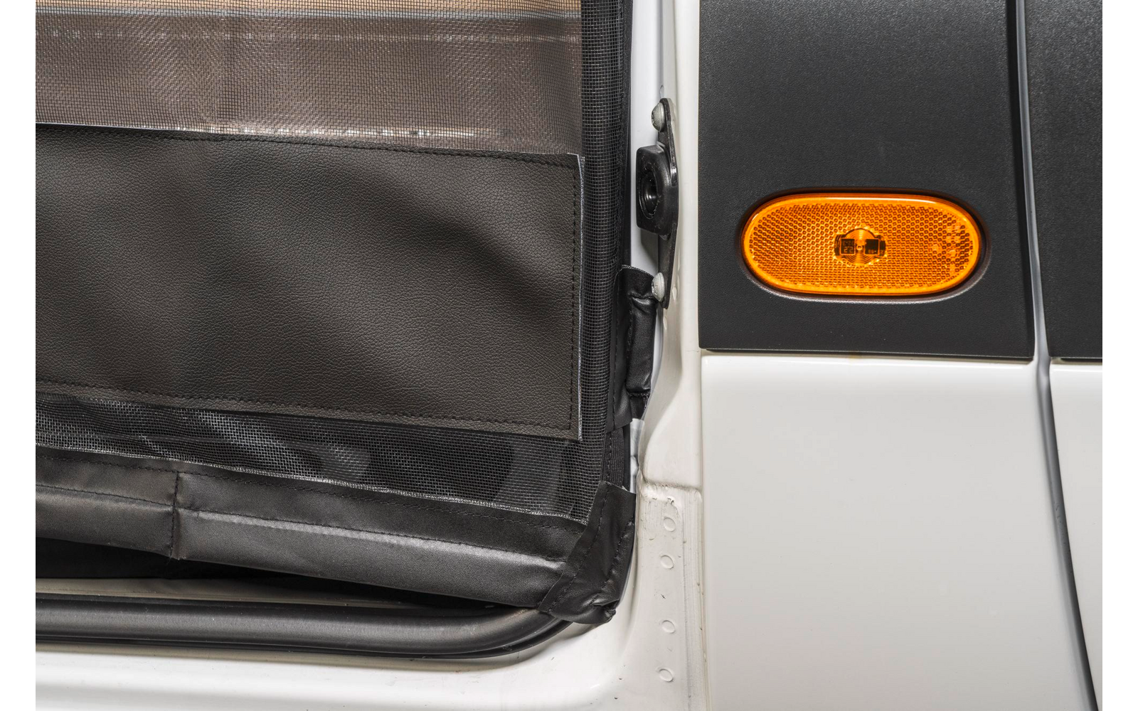 Nahaufnahme eines orangen Blinkers an einem weißen Fahrzeug neben einer geöffneten Tür mit schwarzem Innenraum