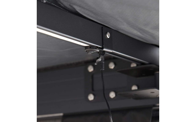 Unterseite eines Metallrahmens mit Matratzenkante, runder Stecker mit Kabel hängt an der Rahmenstange, sichtbare Schrauben