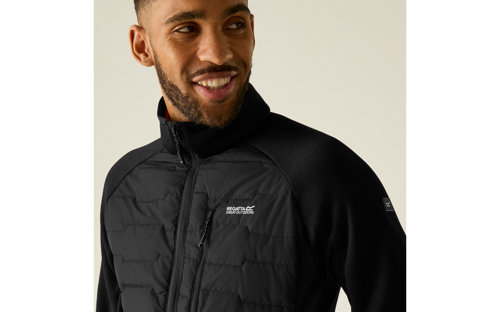 Porträt einer lächelnden männlichen Person von Brust bis Kopf, trägt eine schwarze Jacke mit gesteppter Vorderseite und Reißverschluss, sichtbares Logo Regatta Great Outdoors