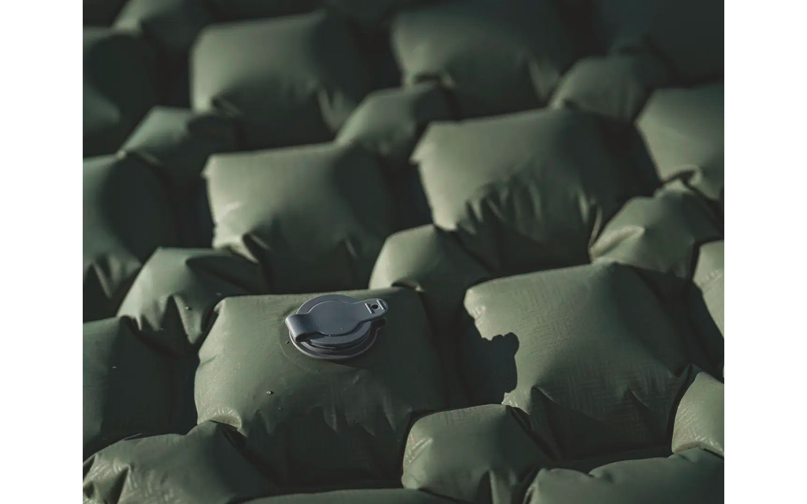 Nahaufnahme einer grünen aufblasbaren Isomatte mit aufgesetzter schwarzer Schlafmaske