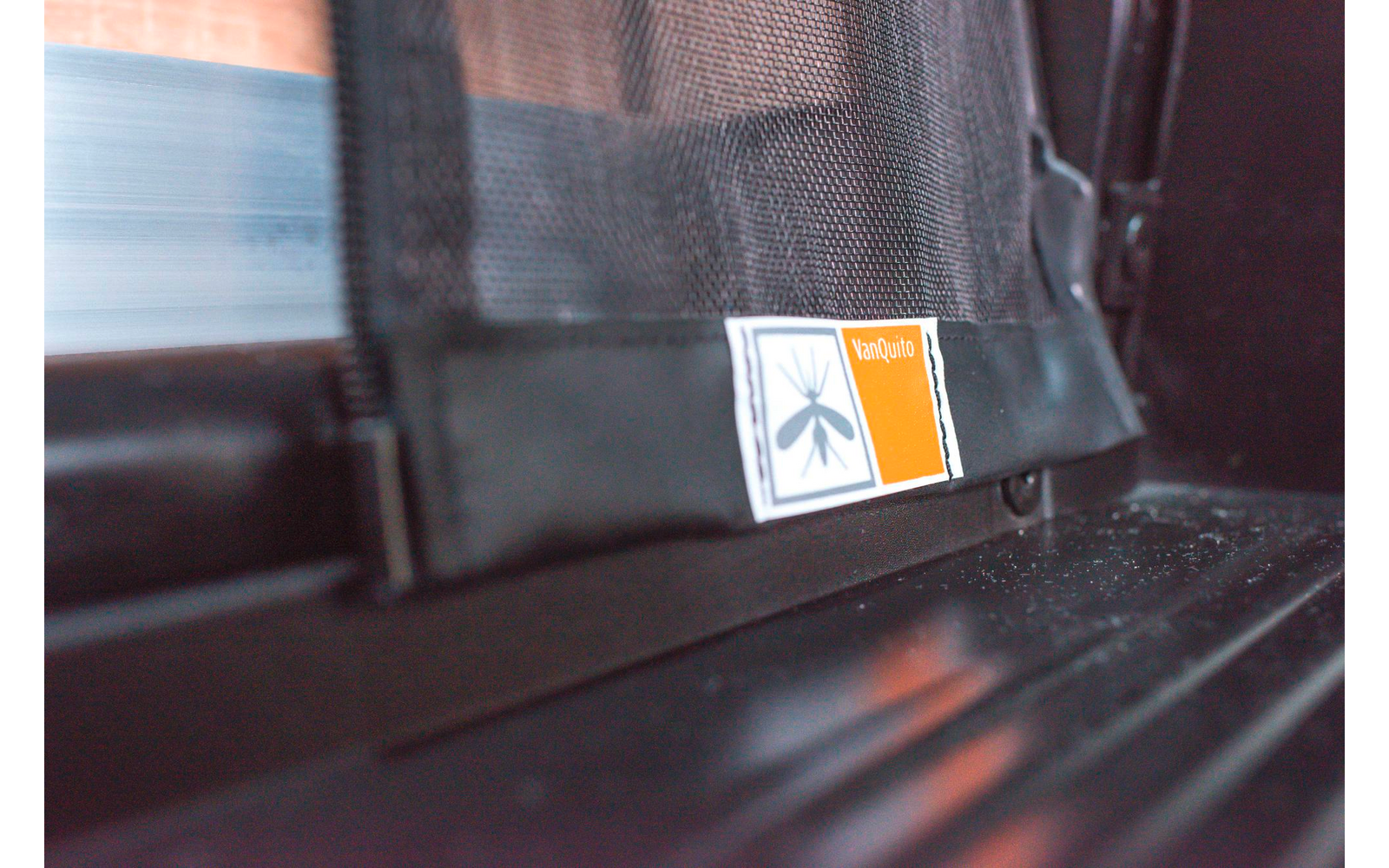 Ein orangenes Warnschild mit einem stilisierten Hund an einer Leine auf einem Fensterrahmen