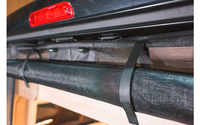 Nahaufnahme eines schwarzen Zurrgurts an einem grauen Gepäckträger eines Fahrzeugs