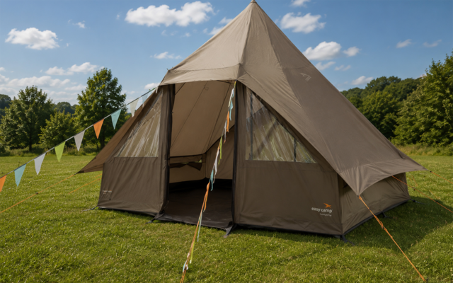 Beige tent with open entrance on green grass, bunting attached to a guyline, blue sky with a few clouds, trees in the background