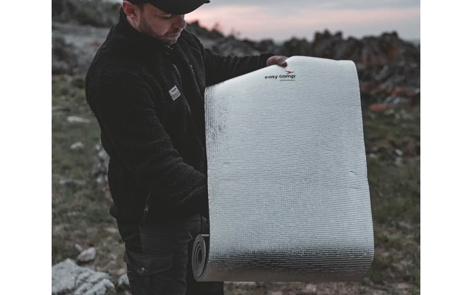 Person hält eine große rechteckige Metallplatte mit abgerundeten Ecken