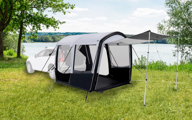 Aufblasbares Zelt vor einem weißen Auto auf einer Grasfläche neben einem See
