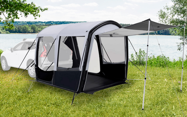 Aufblasbares Zelt vor einem weißen Auto auf einer Grasfläche neben einem See