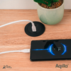 Smartphone draadloos opladen op een zwarte oplaadpad, naast een plant in een groene pot op een houten tafel