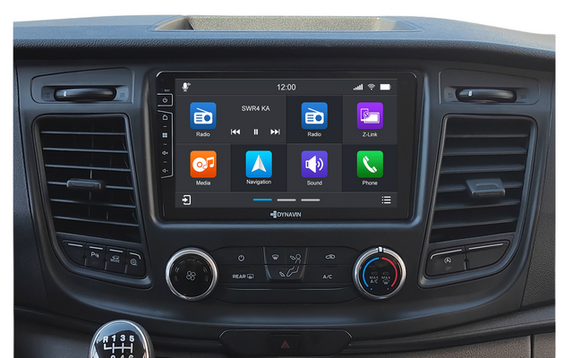 Console centrale de voiture avec grand écran tactile affichant icônes d'apps, bouches d'aération, boutons de climatisation et levier de vitesse manuel avec schéma