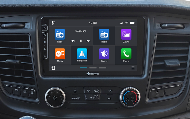 Mittelkonsole eines Autos mit großem Touchscreen mit App-Symbolen, Luftschlitzen, Drehreglern für Klima und Handschalthebel mit Schaltmuster