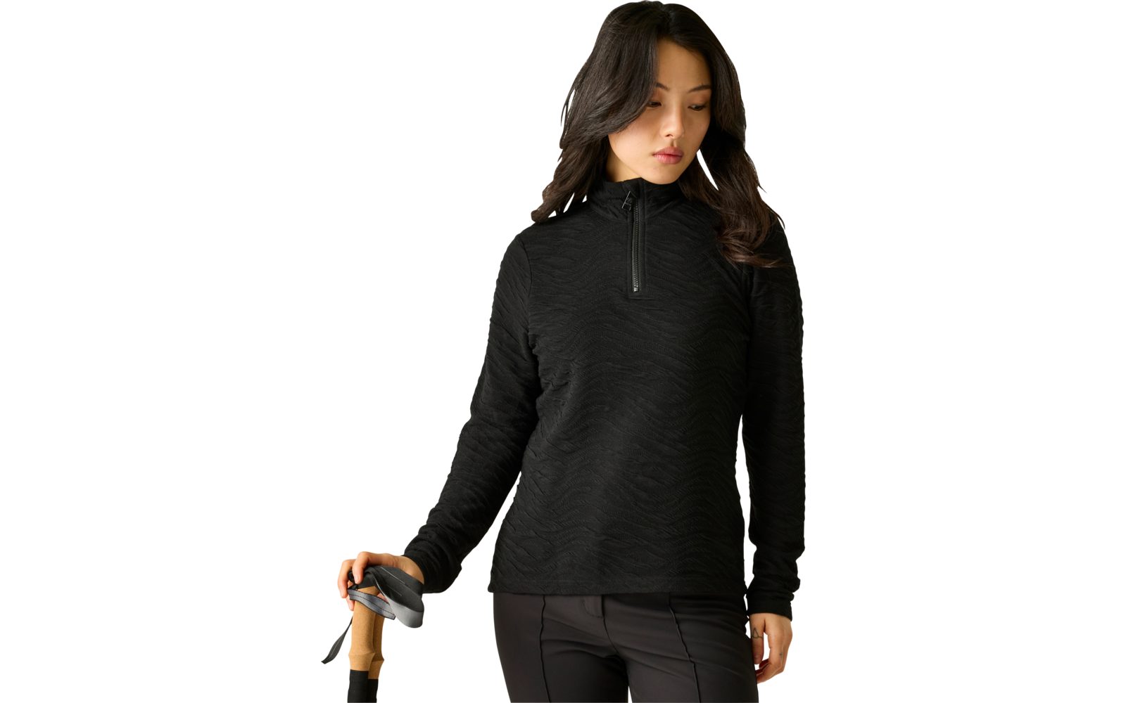 Frau mit dunklen, schulterlangen Haaren in schwarzem, strukturiertem Langarm-Pullover mit kurzem Reißverschluss, hält einen Stock mit Holzgriff, heller Hintergrund