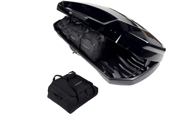 Coffre de toit noir ouvert contenant trois sacs de voyage noirs ; un sac similaire posé à côté sur fond blanc