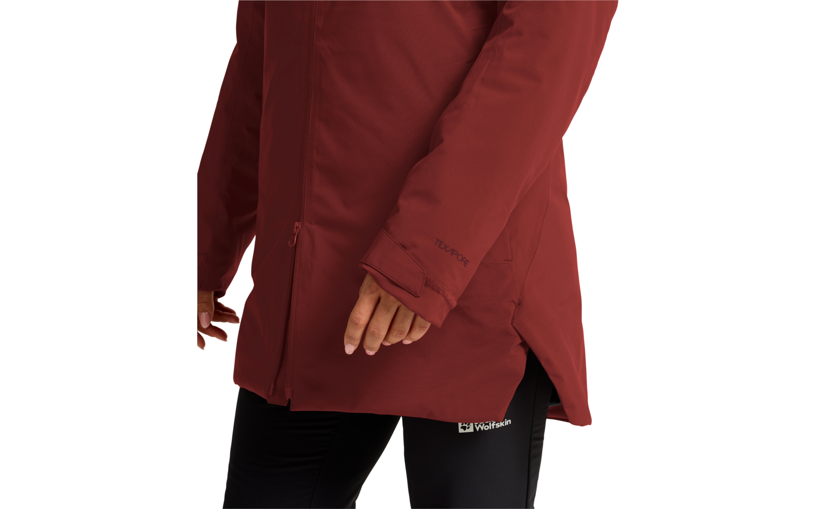 Vista parcial de una persona con chaqueta acolchada rojo oscuro con cremallera y abertura lateral, mano visible, mallas negras con logotipo blanco 'Wolfskin'