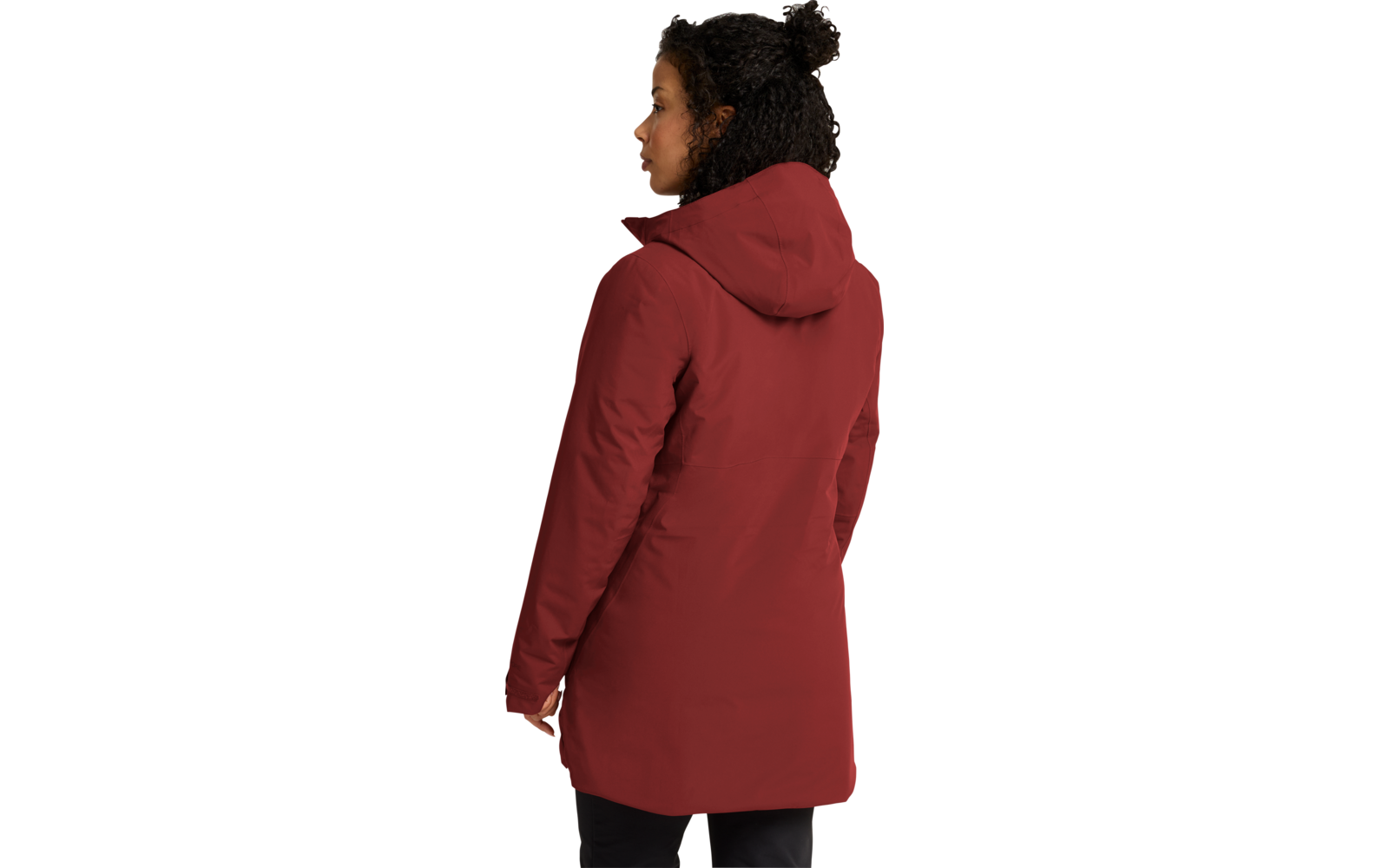 Persona con cabello oscuro y rizado recogido en un moño, vista de espaldas en ligero perfil hacia la izquierda, viste un abrigo rojo con capucha y pantalones negros