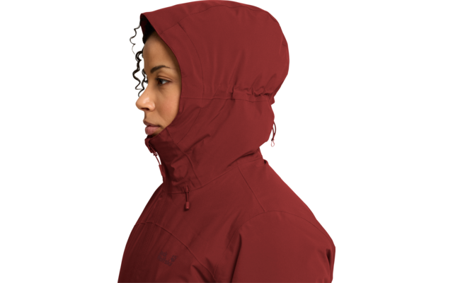 Persona de perfil mirando a la izquierda, rostro visible, lleva una chaqueta con capucha rojo oscuro, capucha levantada y cremallera cerrada