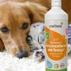 Brauner Hund und grau-weiße Katze liegen nebeneinander auf hellem Teppich; weiße Flasche mit Etikett 'awiwa pet Mikrobiologischer Geruchsentferner und Reiniger' im Vordergrund