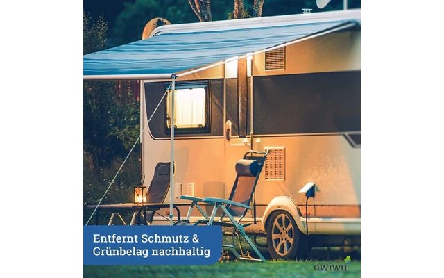 Wohnwagen mit ausgefahrener Markise, zwei Klappstühlen, kleinem Tisch mit Laterne, beleuchtetem Fenster und Rasen; sichtbarer Text: "Entfernt Schmutz & Grünbelag nachhaltig"