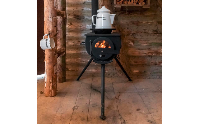 Schwarzer, runder Holzofen auf drei Beinen mit sichtbarer Flamme, weißer Kessel auf dem Ofen, weißer Becher an einem Holzbalken, Holzblockwand und Holzboden