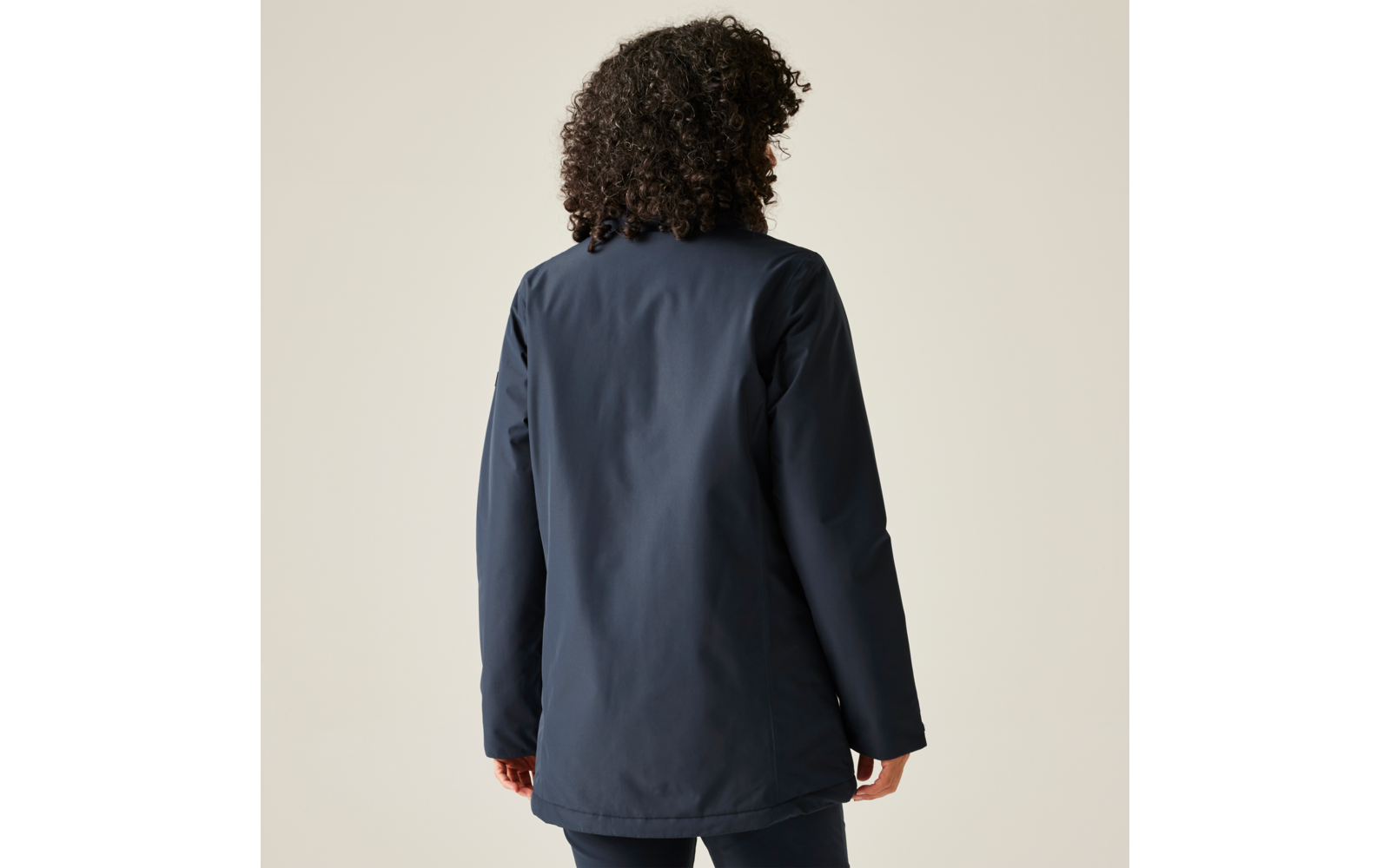 Personne aux cheveux bouclés vue de dos portant une veste bleu foncé