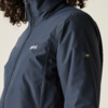Dunkelblaue Jacke mit Stehkragen und durchgehendem Reißverschluss, kleines Logo auf linker Brust, kleines quadratisches Label am rechten Oberarm, lockige Haare am oberen Bildrand, heller Hintergrund