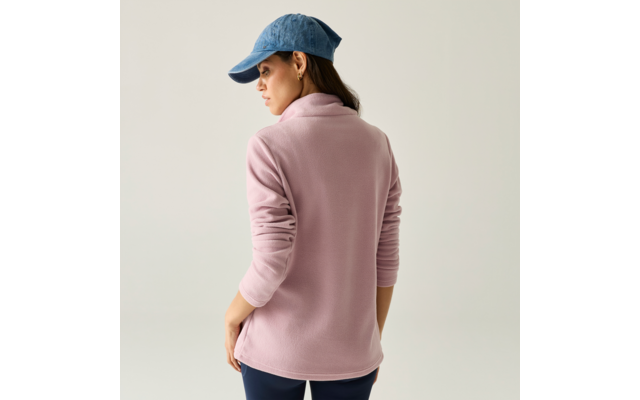 Persona vista da dietro che indossa una giacca in pile rosa, un berretto blu e pantaloni scuri su uno sfondo chiaro uniforme