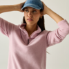 Persona con un berretto da baseball blu e un maglione rosa, mani sul berretto