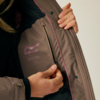Person öffnet den Reißverschluss einer braunen Jacke