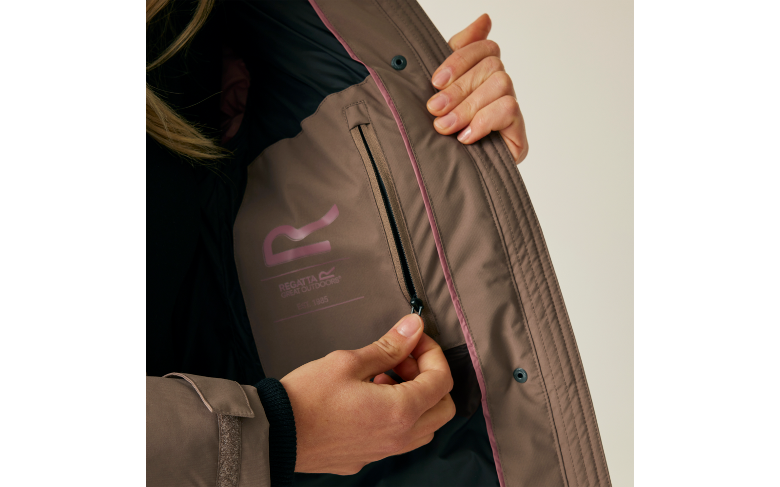 Person öffnet den Reißverschluss einer braunen Jacke