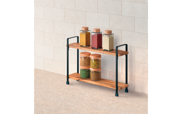 Zweistufiges Holzregal mit schwarzem Metallgestell vor heller gefliester Wand; auf dem oberen Brett drei quadratische Glasbehälter mit Holzdeckeln gefüllt mit gelbem, rotem und beigem Material; auf dem unteren Brett mehrere runde Glasbehälter mit Hol