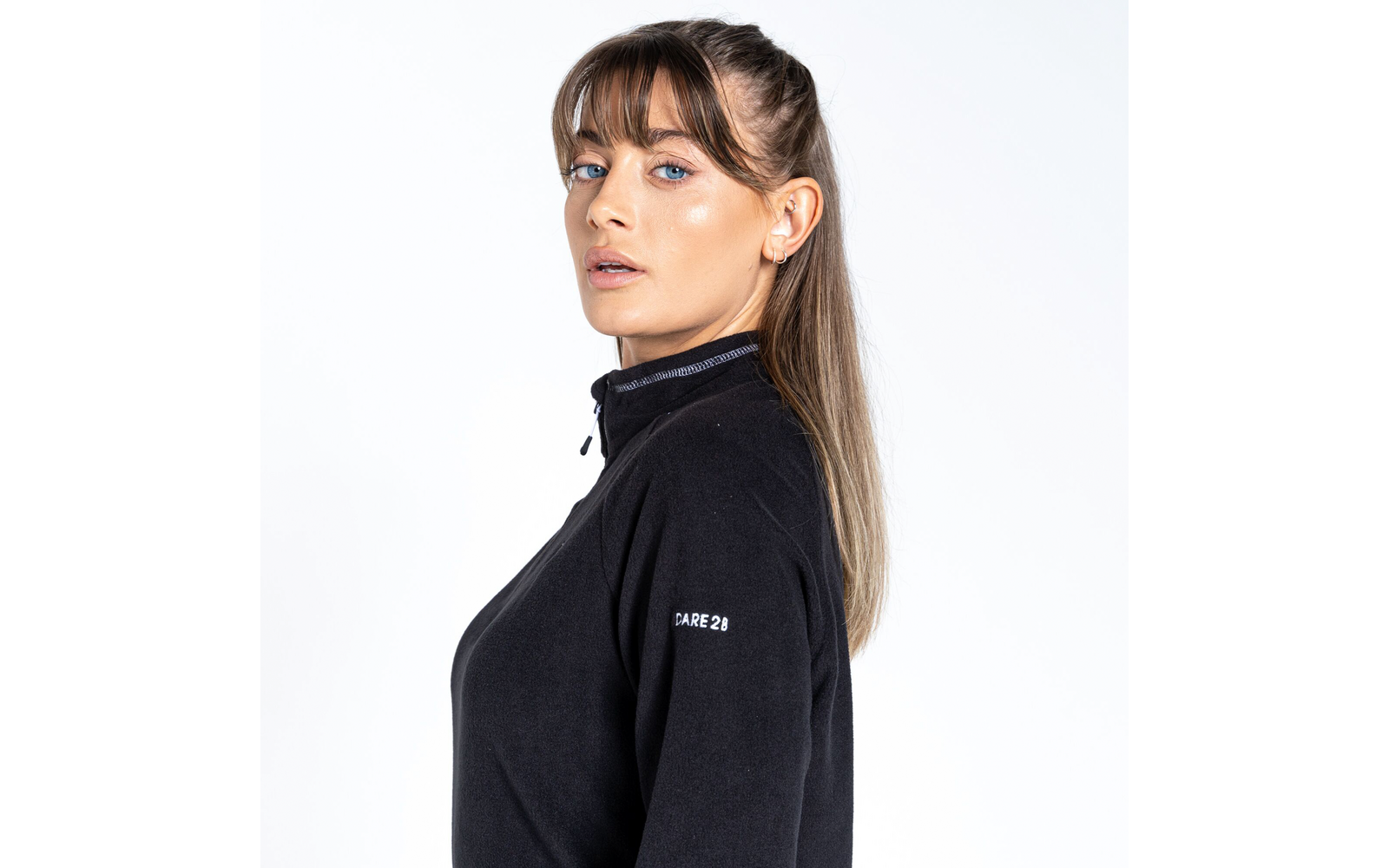 Porträt einer Frau mit hellem Teint und braunen Haaren, die seitlich schaut und einen schwarzen Pullover trägt
