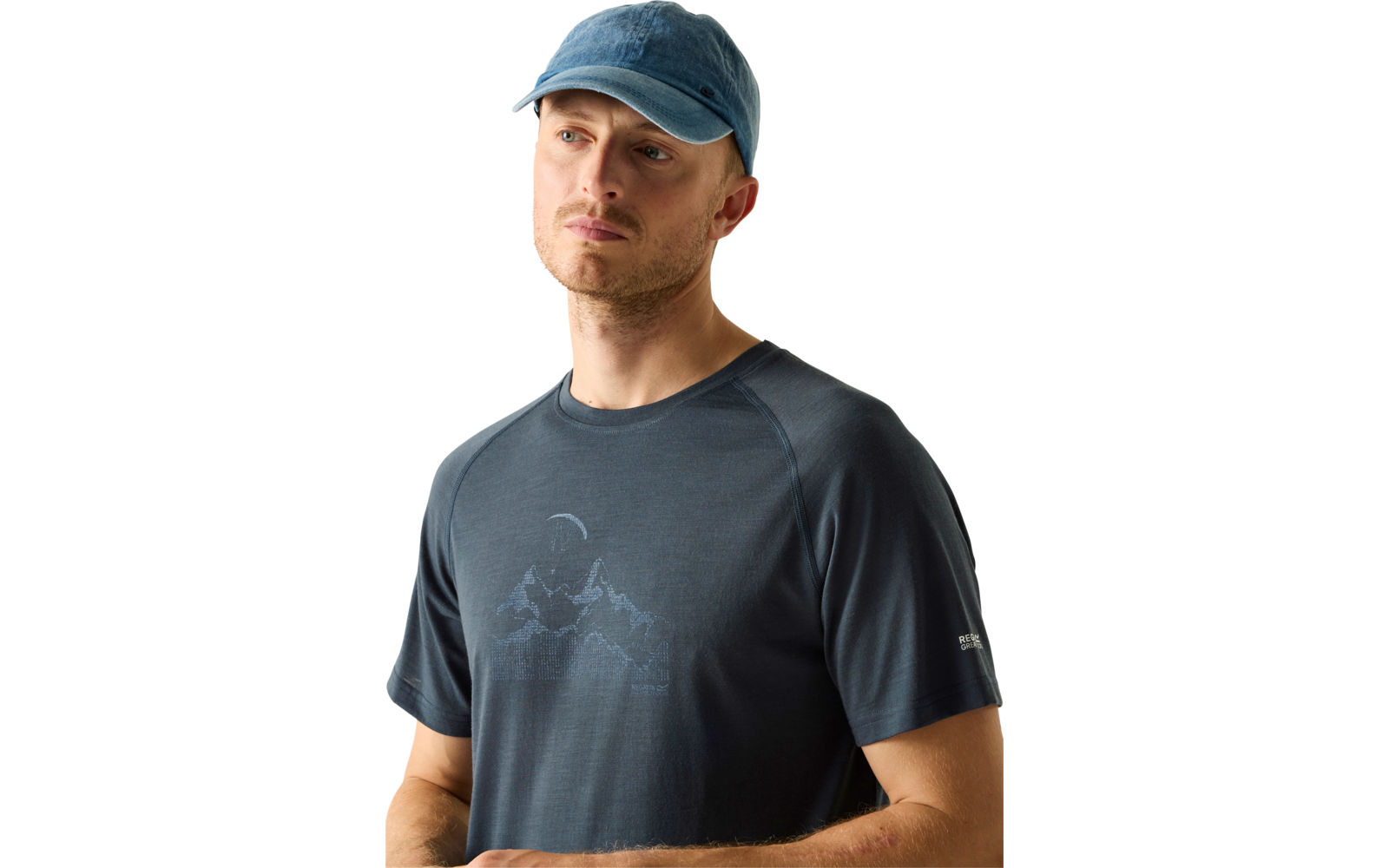 Mann mit kurzem Bart, blaue Baseballkappe, dunkles T‑Shirt mit Bergmotiv, schaut nach links, Arme vor dem Körper