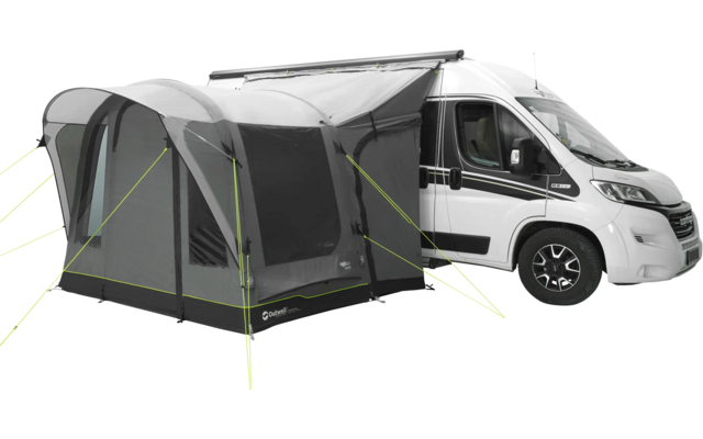 Weißer Wohnmobil mit angebautem grauem Vorzelt auf einer Wiese