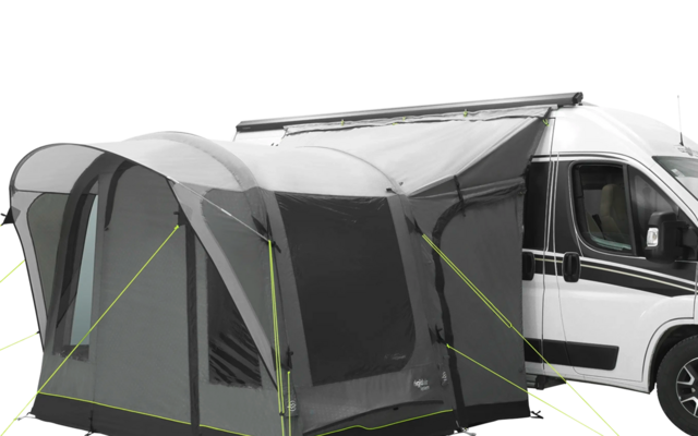 Camper bianco con tenda grigia annessa su un prato