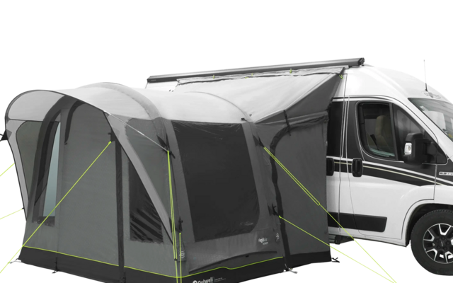 Weißer Wohnmobil mit angebautem grauem Vorzelt auf einer Wiese